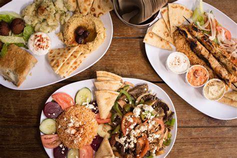 A table filled with various authentic Greek dishes including moussaka and souvlaki at Taverne Grecque.