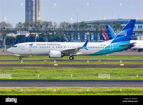 A Garuda Indonesia airplane at an airport with passengers walking towards it.