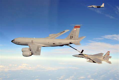 A KC-135 Stratotanker refueling fighter jets in mid-air.