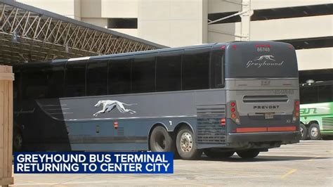 A Greyhound intercity bus at a busy terminal with people boarding.